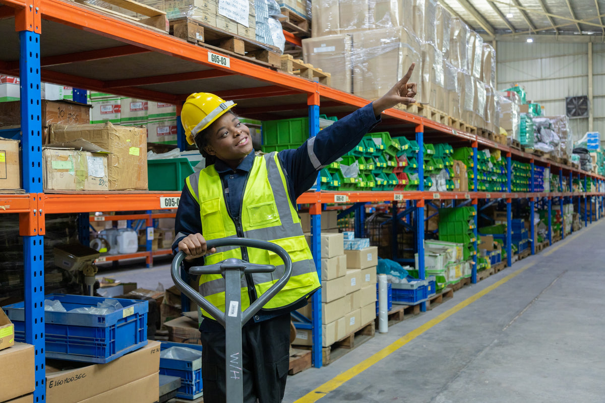 Woman operating a forklift in a warehouse wearing utility work gloves, durable warehouse gloves designed for machinery handling.